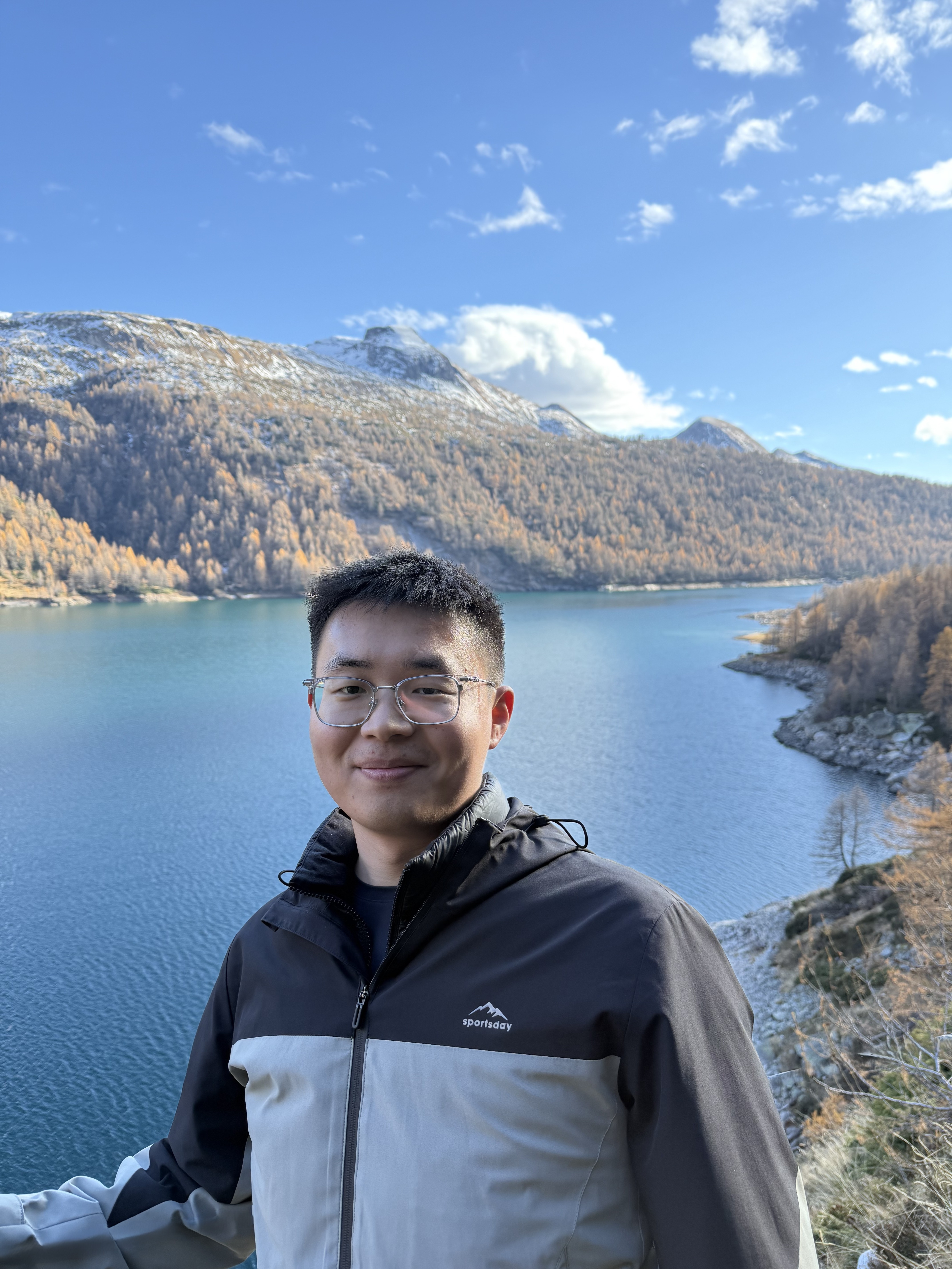 Kun Xu in front of a mountain lake